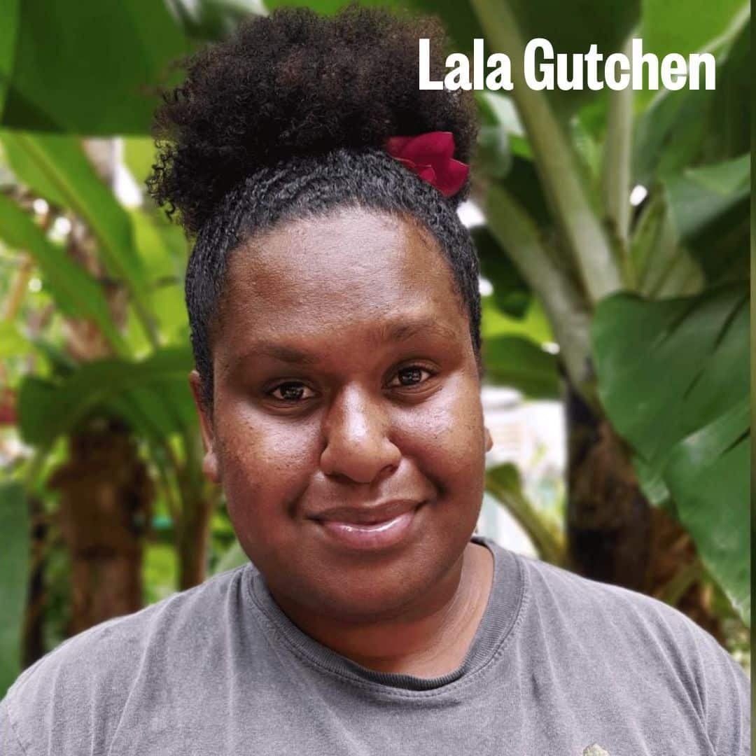A photo of Lala Gutchen smiling toward camera in front of trees
